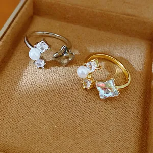 Detailed view of gold and silver open rings with zircons and pearls in a jewelry box