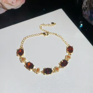 Elegant close-up of 18k gold plated bracelet featuring red stones and floral details