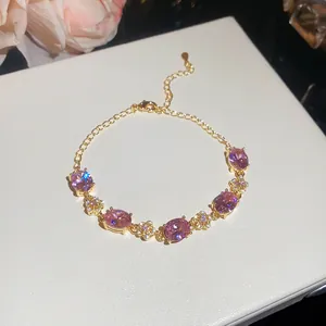 Close-up of pink oval zircon stones and delicate gold floral links on bracelet