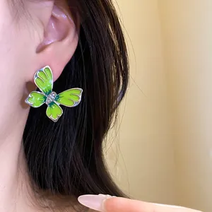 Close-up of lime green enamel butterfly earring with sparkling rhinestone center on model ear.