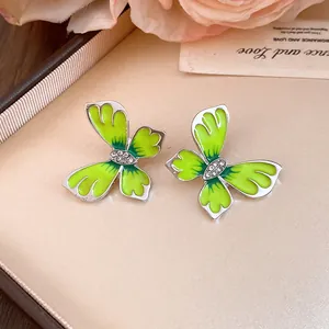 Detailed macro view of lime green enamel butterfly stud earrings with sparkling crystal centers