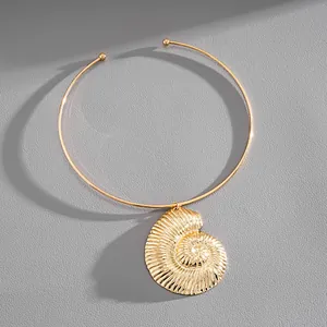 Close-up of vintage gold conch shell pendant on a minimalist metal choker necklace