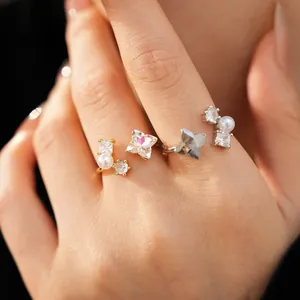 Detailed macro shot of elegant zircon flower and pearl open rings on model fingers