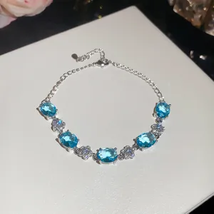 Detailed view of silver-plated bracelet with oval blue zircons and flower charms