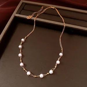 Elegant 18k gold plated double-layer pearl necklace with beads on dark jewelry tray.