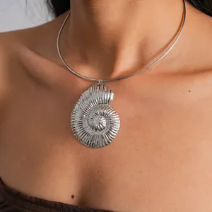 Detail of a vintage silver metallic nautilus shell pendant necklace on a collar.
