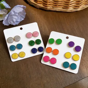 Colorful round enamel stud earrings set with gold-tone trim on white display cards