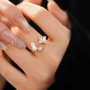 Detail of gold open ring with zircon flower and pearl on hand