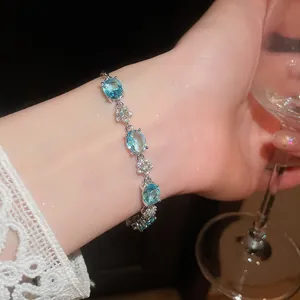 Close-up of 18k gold plated bracelet with blue oval cubic zirconia and flower links