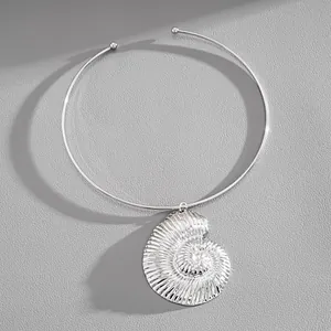 Detail view of a vintage silver textured conch shell pendant on a minimalist metal collar.
