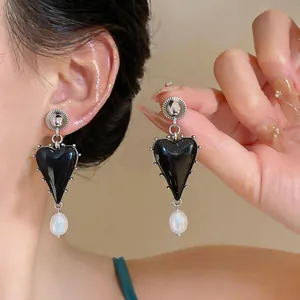 Close-up detail of vintage style black resin heart earrings with white pearl drops on model