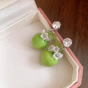 Nahaufnahme von grünen Apfel-Ohrhängern aus Harz mit Blüten-Details und Zirkonia.