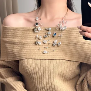Detail view of a multi-layer vintage pearl necklace worn with a knit sweater