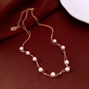 Detailed view of 18k gold plated pearl necklace on elegant vintage dark brown fabric.