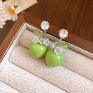 Nahaufnahme von frischen grünen Apfel-Harz-Ohrringen mit Zirkon und Blütendetails