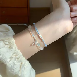 Fresh beaded and woven blue cord bracelet set with silver fish charm on a model's wrist
