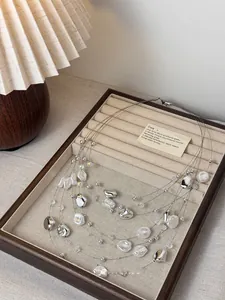 Detail view of layered pearl necklace with irregular beads in a luxury display box