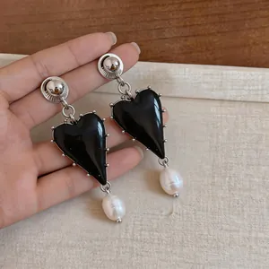 Detailed view of vintage heart-shaped resin earrings with elegant white pearl drops