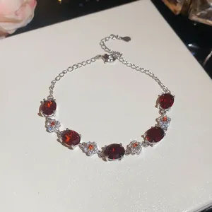 Detail view of silver-toned bracelet featuring vibrant oval red stones and delicate flowers