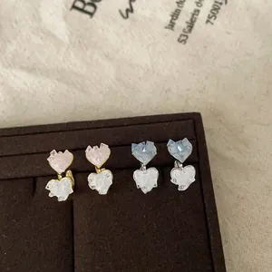 Detail view of sweet gradient glass heart earrings in pink and blue on a velvet stand