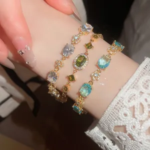 Detailed view of three 18k gold plated bracelets with colorful oval zircons on a wrist.