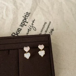 Detailed view of pink and white heart-shaped textured glass stud earrings in gold