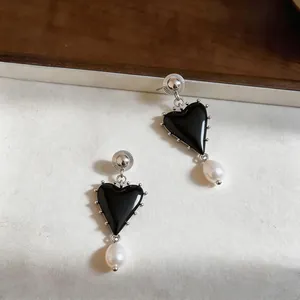 Detailed view of vintage black resin heart earrings with elegant white pearl drops