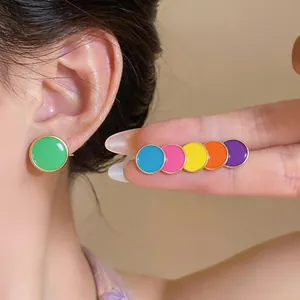 Detailed close-up of vibrant colorful round enamel stud earrings on a model's ear
