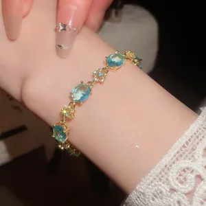 Close-up of elegant 18k gold plated bracelet with light blue oval zircons and flower links