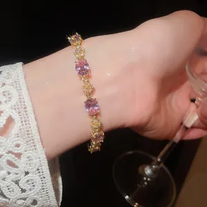 Close-up of elegant 18k gold plated bracelet with pink oval zircons on a lady's wrist.