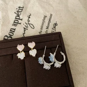 Detailed shot of sweet gradient heart glass earrings and hoops on velvet display stand