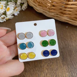 Close-up detail of colorful round enamel stud earrings set on a white display card