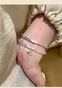 Close-up of blue beaded bracelet with silver fish charm and clear crystal bead strand.
