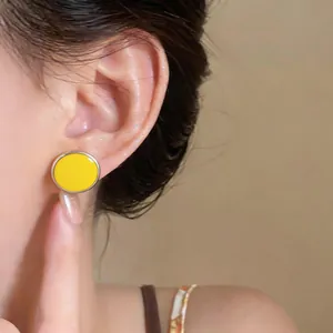 Close-up of vibrant yellow round oil-drop stud earrings on a model's ear