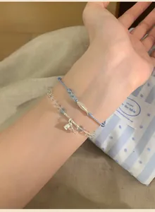 Detailed shot of handmade blue braided rope bracelet with silver fish pendant