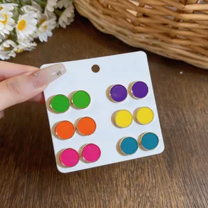 Detailed view of six pairs of colorful round enamel stud earrings on display card