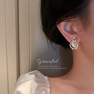 Detailed view of elegant gold-tone cat's eye stone earrings with crystals on ear