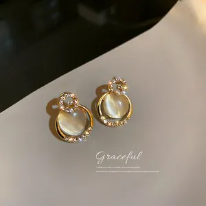 Detailed macro view of cat's eye stone earrings with sparkling rhinestone letter G