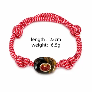 Close-up of red and white braided rope bracelet with natural tiger eye stone center