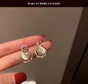 Elegant gold-tone cat's eye stone stud earrings featuring sparkling rhinestone accents