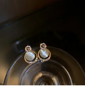 Detailed view of elegant gold-toned cat's eye stone stud earrings with rhinestones