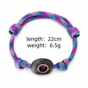 Macro detail of colorful braided rope bracelet featuring natural stone and purple gemstone inlay