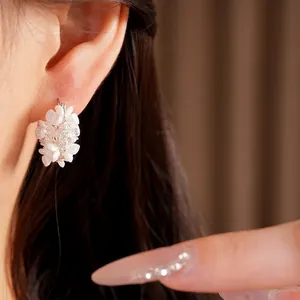 Elegant flower basket earrings with white blossoms and zircon accents on model