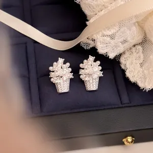 Macro view of elegant silver flower basket earrings with zircon and pearls in a box