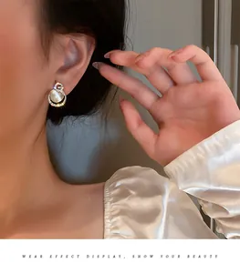 Close-up of model wearing cat's eye stone earrings with silver needles and crystal details