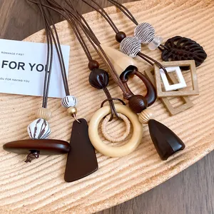 Gros plan de divers colliers pendentifs en bois et résine de style bohème sur un plateau