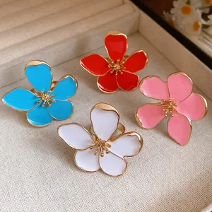 Detail view of colorful enamel flower rings with gold-plated metal frames and open band design