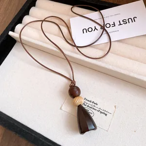 Vue détaillée d'un collier pendentif en résine marron avec des perles crème et cordon