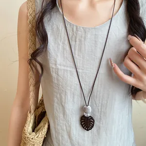 Vue détaillée du collier avec pendentif en feuille de résine et cordon en cuir brun
