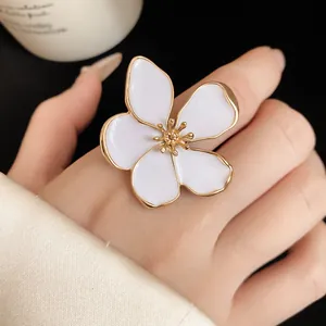 Detail view of large white enamel flower ring showing the gold-plated petal edges